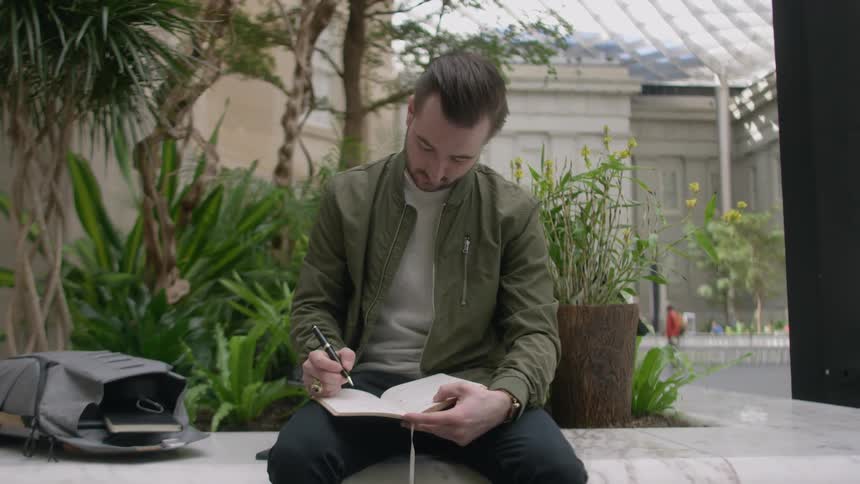 Man writing while sitting on a bench