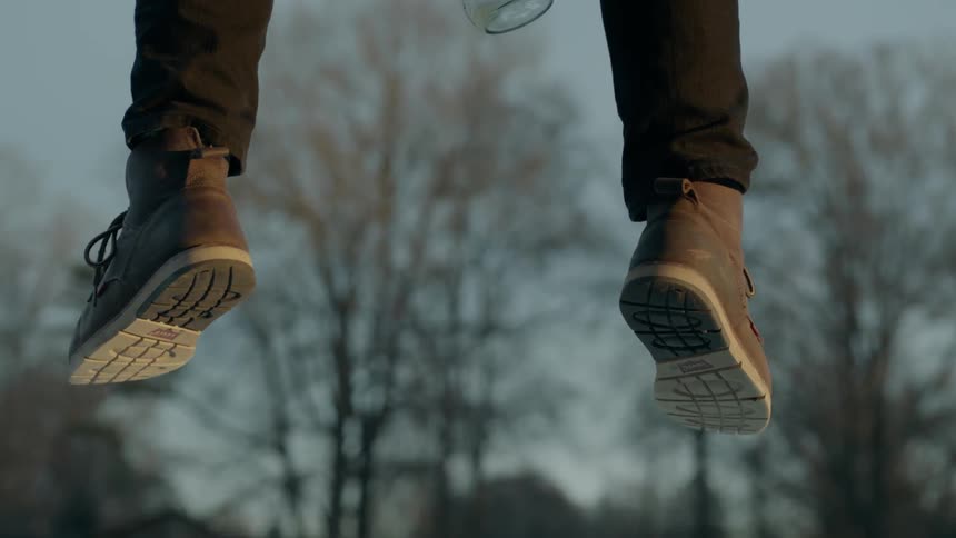 A man's feet are hanging over a ledge outside in daylight