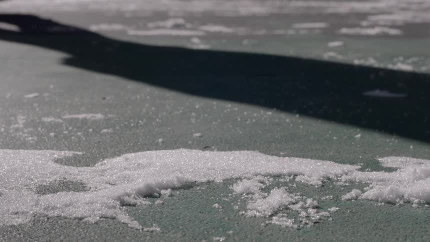 Person casts a shadow as he walks on the snowy pavement