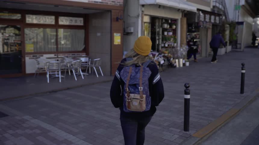 A woman crosses the street on a sunny day