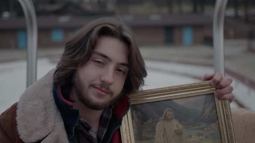 A man poses with a painting of jesus