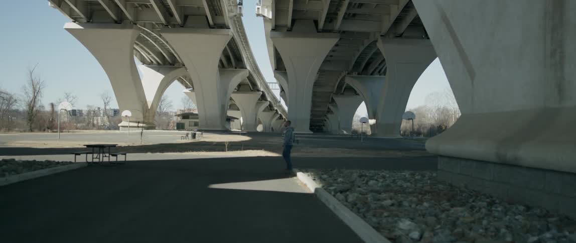 A person walks under the overpass on a sunny day