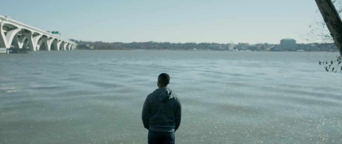 Man looks out at the rough water under a blue sky