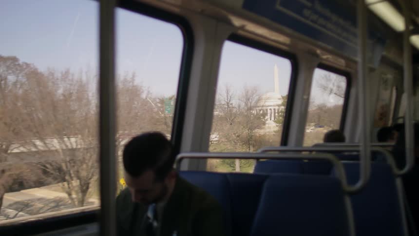 Man riding train with Washington DC monuments in background window