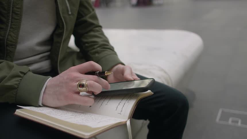 A man is using his phone on his notebook