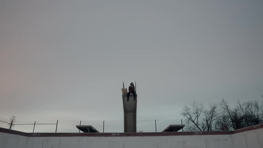 A person sits on the pool platform on a cloudy day