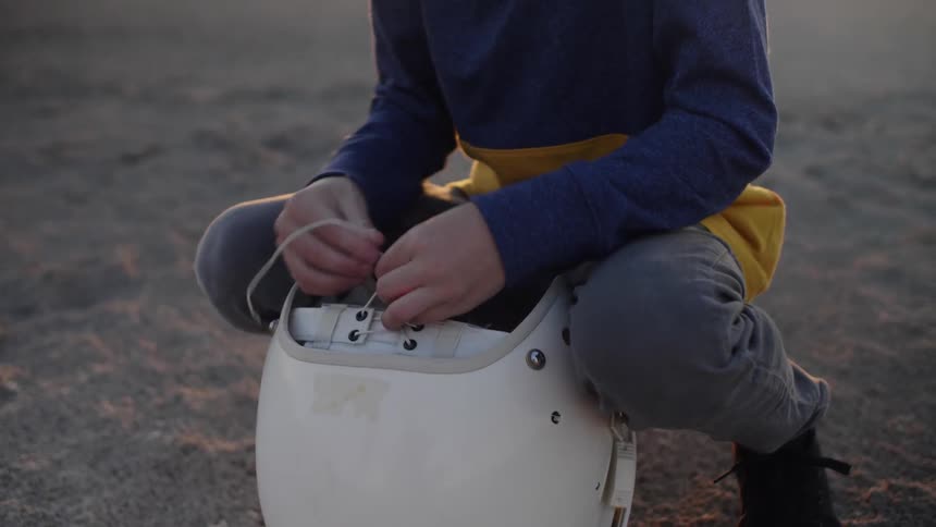 A child ties up the string on his helmet