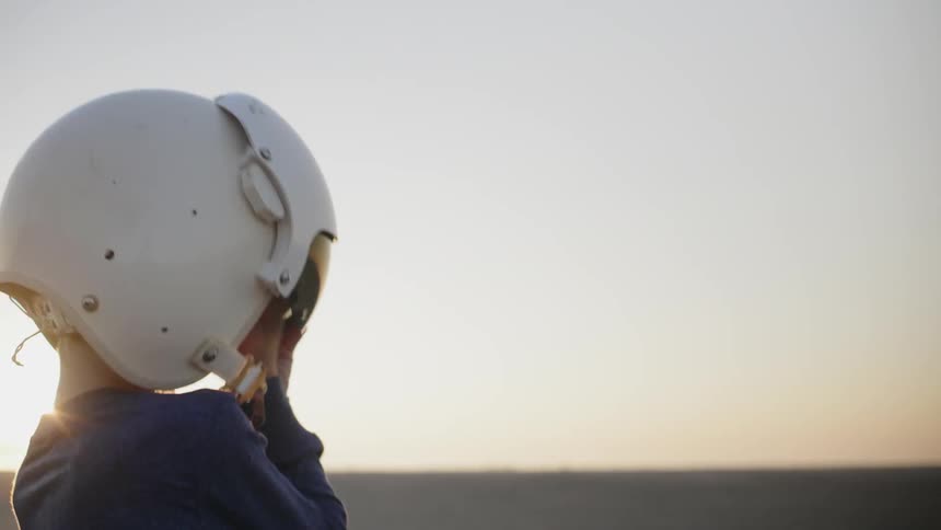 A child fastens the helmet at sunset