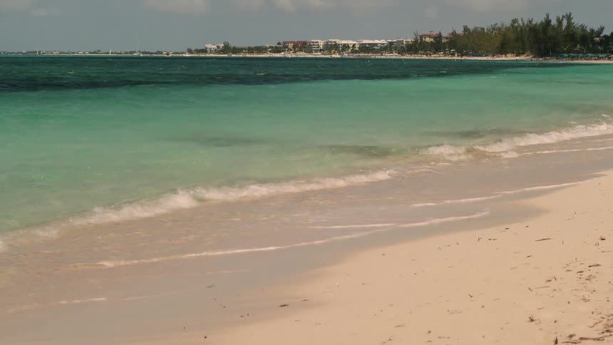 The clear water crashes into the sand