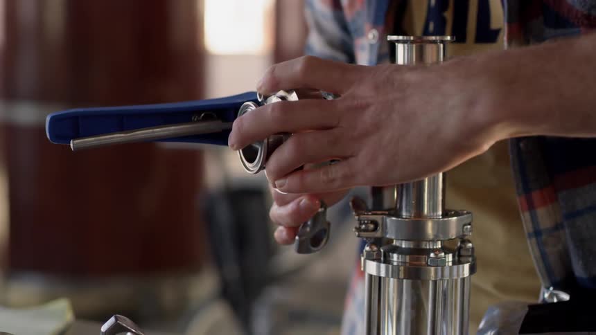 A man is putting together a pipe on a canister inside in daylight