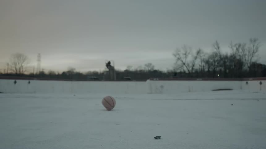 A deflated basketball rolls over the ground