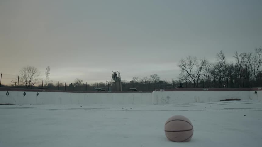 Basketball sits in a snow covered field