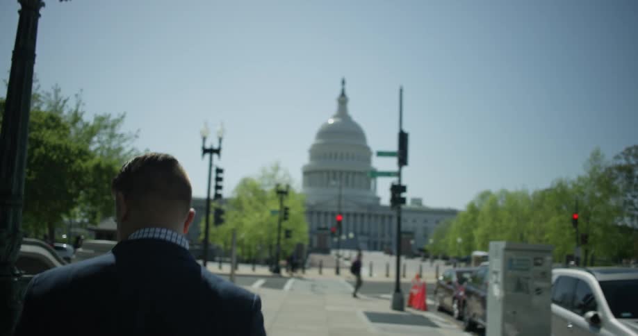 A man walks down the street towards the building