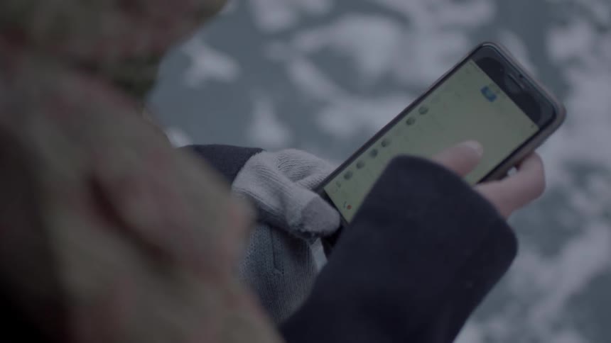 A woman uses her phone in the cold