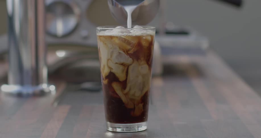 Cream is poured into an iced coffee
