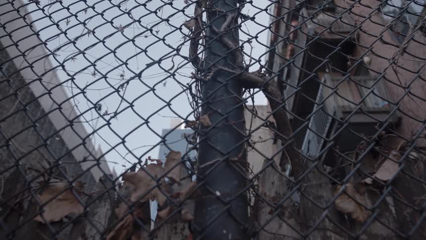 Debris clogs the fence near the buildings