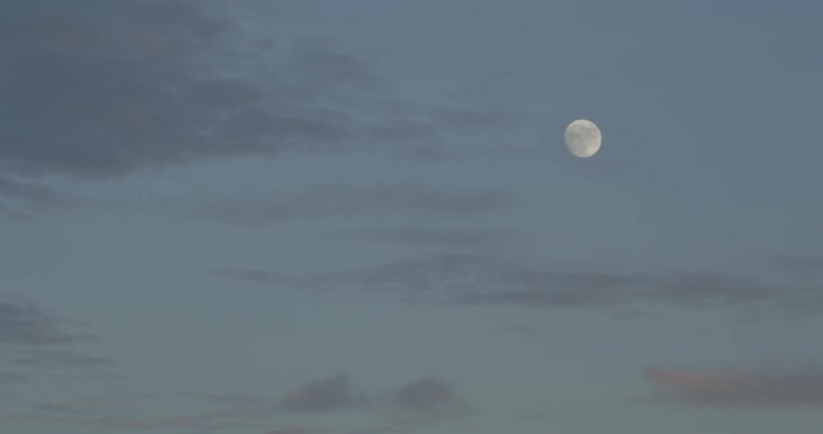 The moon can be seen in the clear sky at sunset