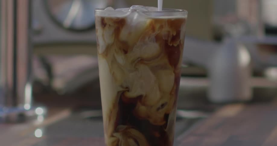 Icy drink sitting on a table with milk being poured into it forming swirls