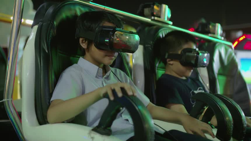 Young kids sit in a ride with vr headsets on