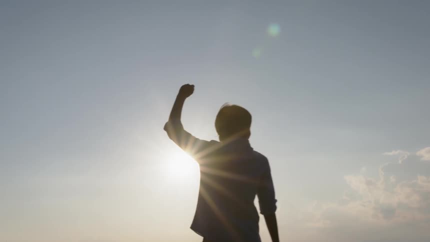 A young man lifts his arm up into the air