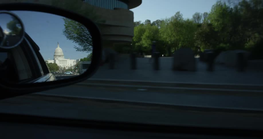 The rearview mirror of the vehicle is showing the capital building
