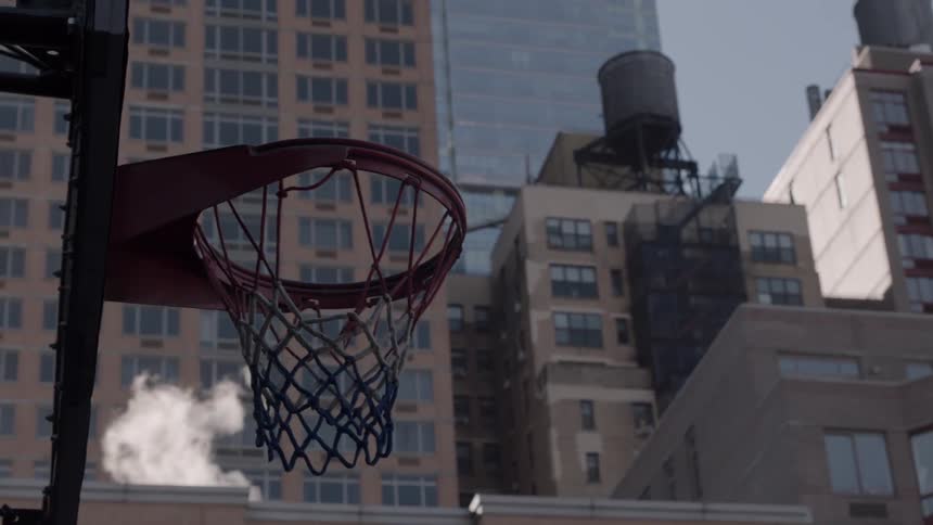 A basketball hoop is hanging still in an urban setting in daylight