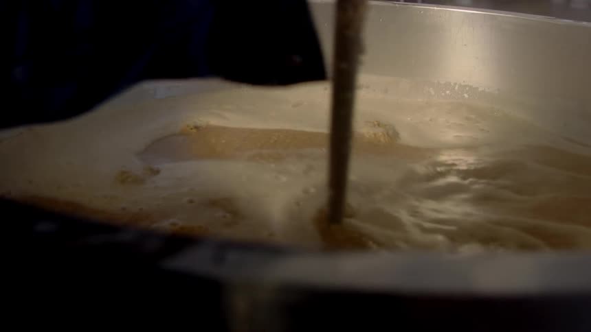 A person stirs liquids in a vat