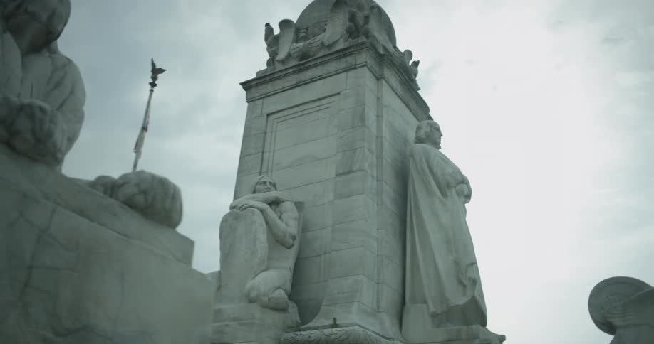 A monumental statue is standing beneath cloudy skies in daylight