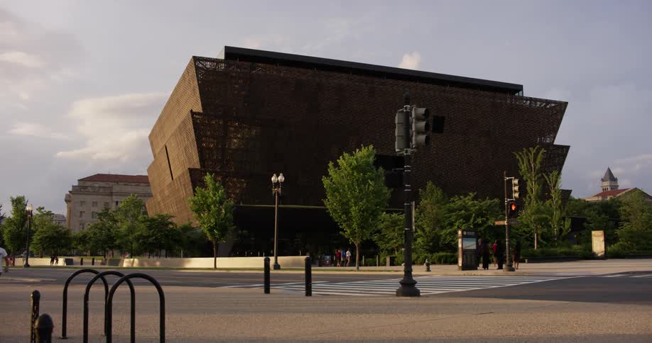 People ride and walk past a large building