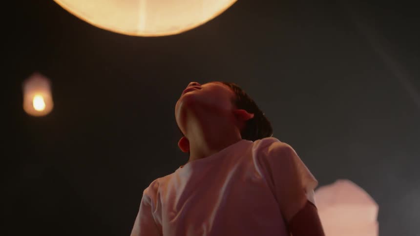 Young boy stares up at a flame burning in a circular shade