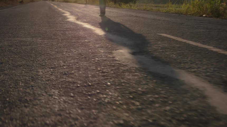 A man walks on a rural road on a sunny day