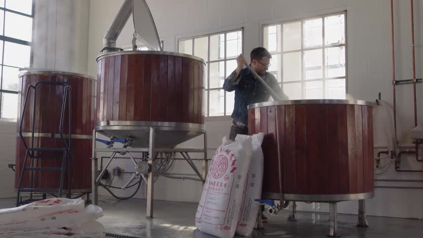Man stirs a large vat in a brewery