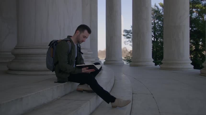 A man reads a book while sitting on marble steps