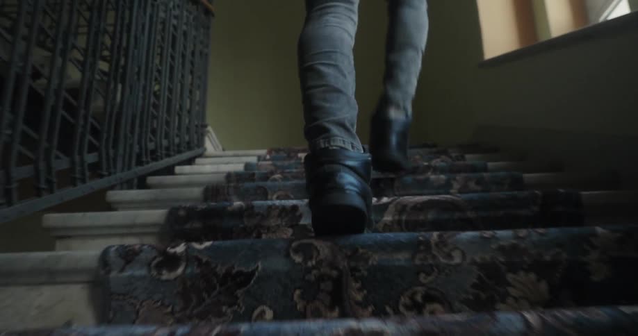 A man is walking up a set of carpeted stairs during the day