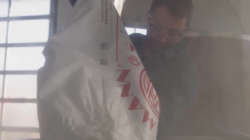 A man is pouring a bag into a container