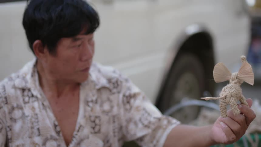 Man looks at a small sculpture made of twine