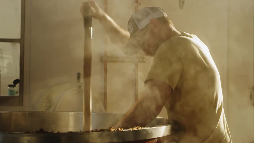 Man uses a shovel to remove hot mud from a large container