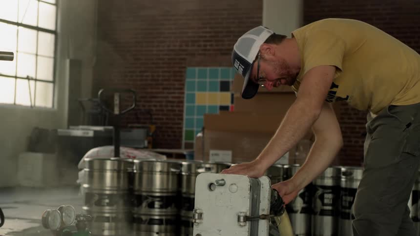 A man adjusts steaming equipment in a brewery