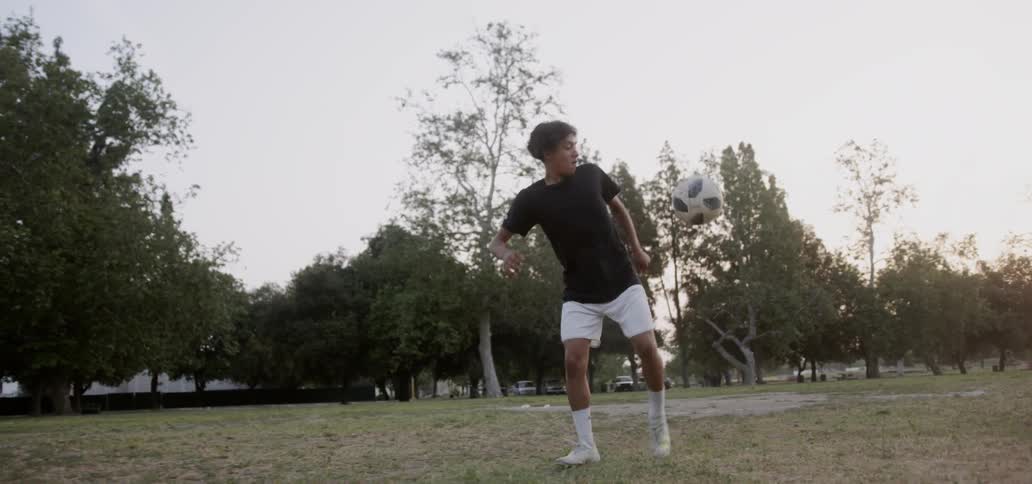 Man kicks a soccer ball in a field