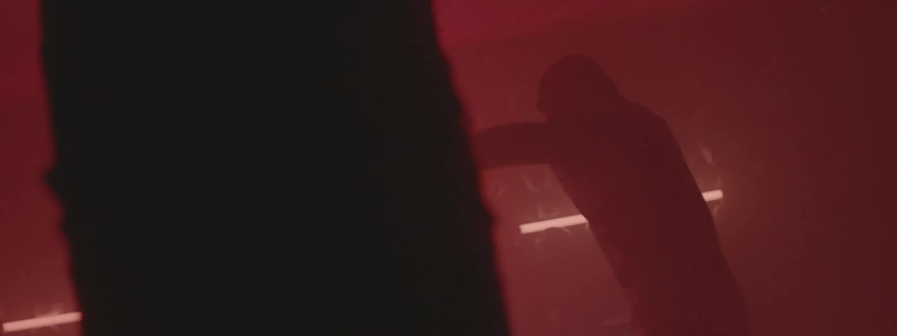 A man is shadow boxing in a dark gym