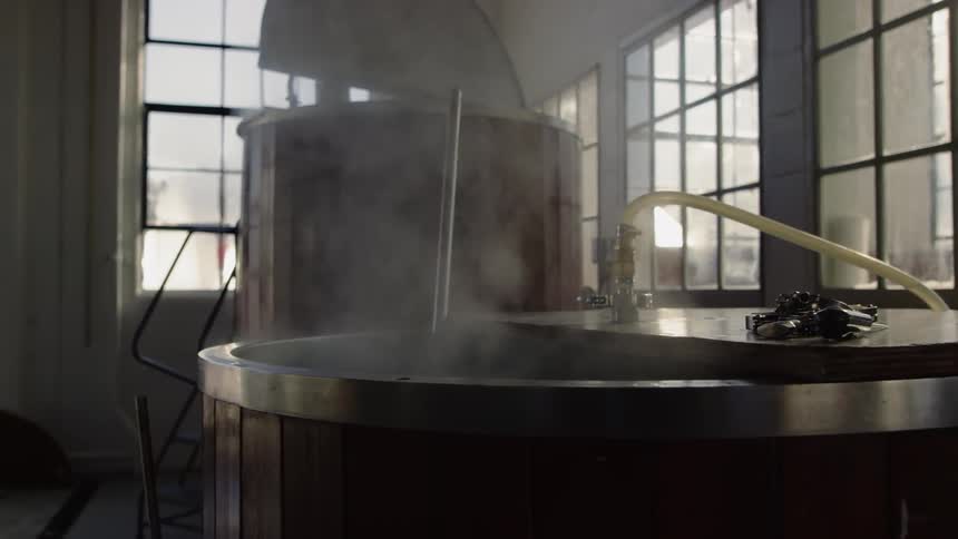The steam is rising from the containers in the brewery