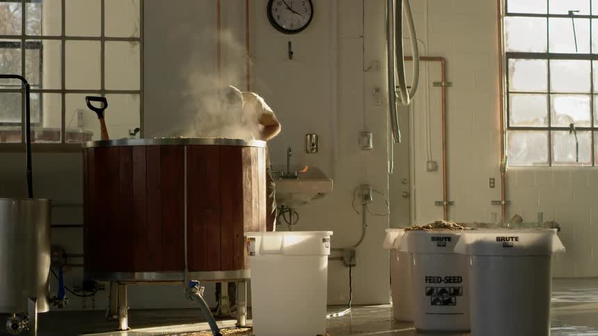 A man is mixing a vat in a brewery