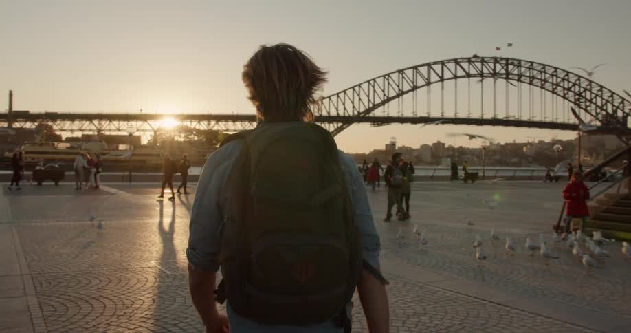 Man wearing a backpack walks towards a bridge