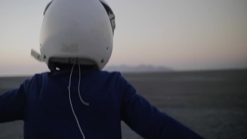 A young boy plays outside with a pilot helmet on