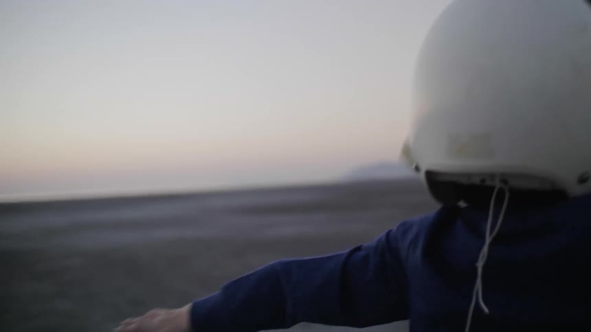 A boy pretends to fly in the desert with a pilot helmet on