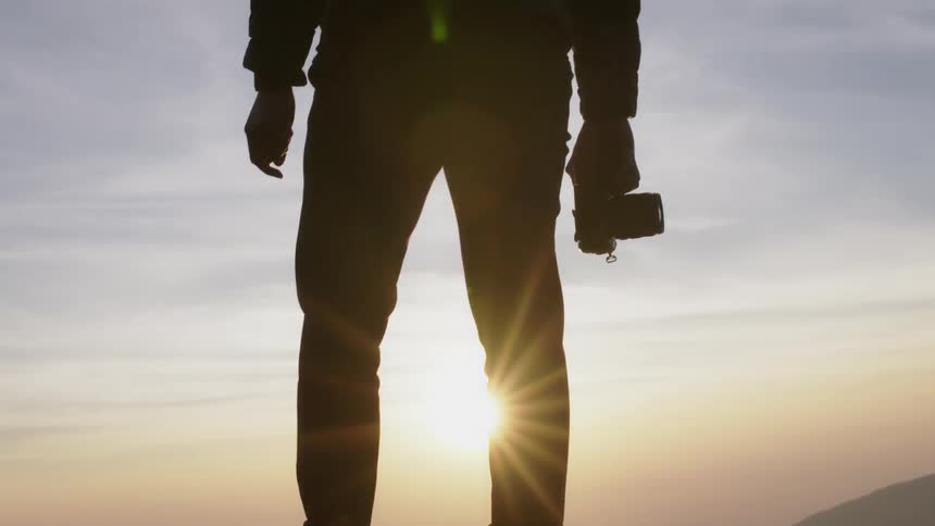 The silhouette of a man holding a camera at sunset