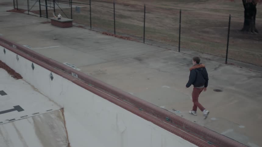 Man walks next to an empty swimming pool