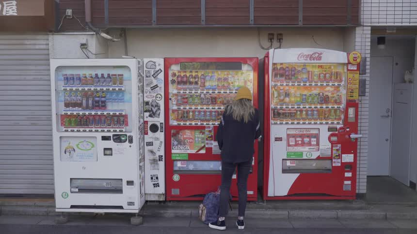 A young woman makes a purchase at a Japanese vending machine