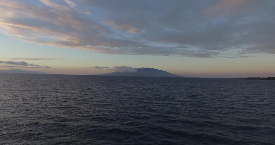 The water flows below sparse clouds and in front of a mountain