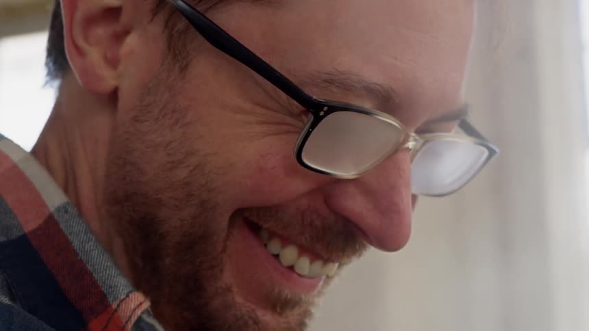 A man smiles and laughs as steam rises from a vat